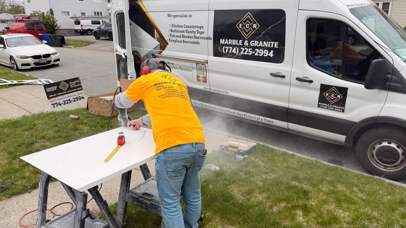 ECR Marble and Granite fabricator cutting a stone slab beside the company work van
